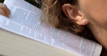 Person with their ear next to an open Bible