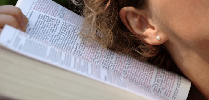 Person with their ear next to an open Bible