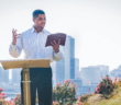 Person preaching outside with a city skyline in the background