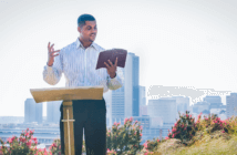 Person preaching outside with a city skyline in the background