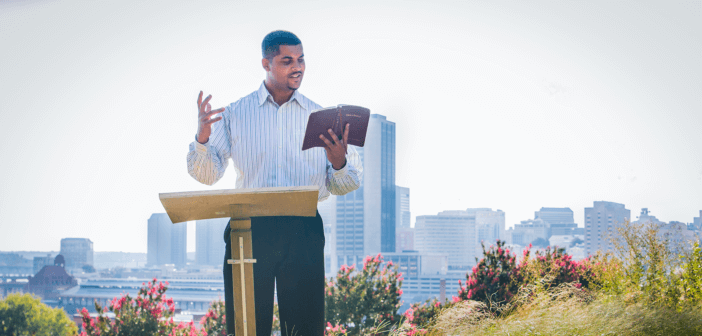 Person preaching outside with a city skyline in the background