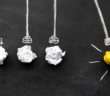 Wadded up paper representing light bulbs in a Newton's cradle. Three are white, and one is yellow, representing an idea. The yellow one is pulled back.